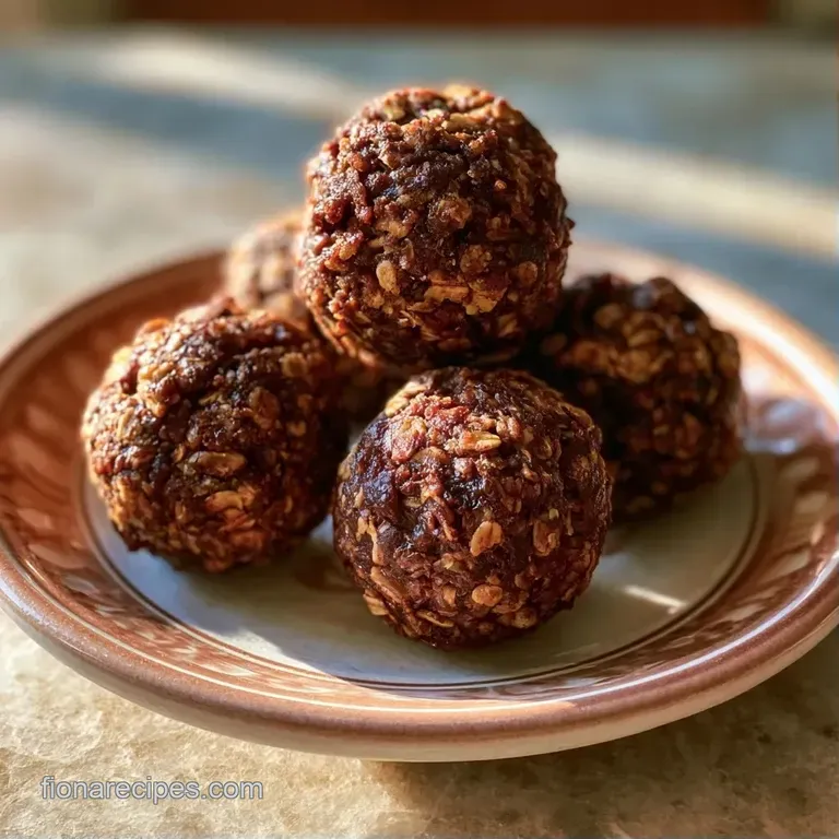 Neatly stacked dark brown energy balls on a slate board, garnished with sea salt and crushed walnuts.